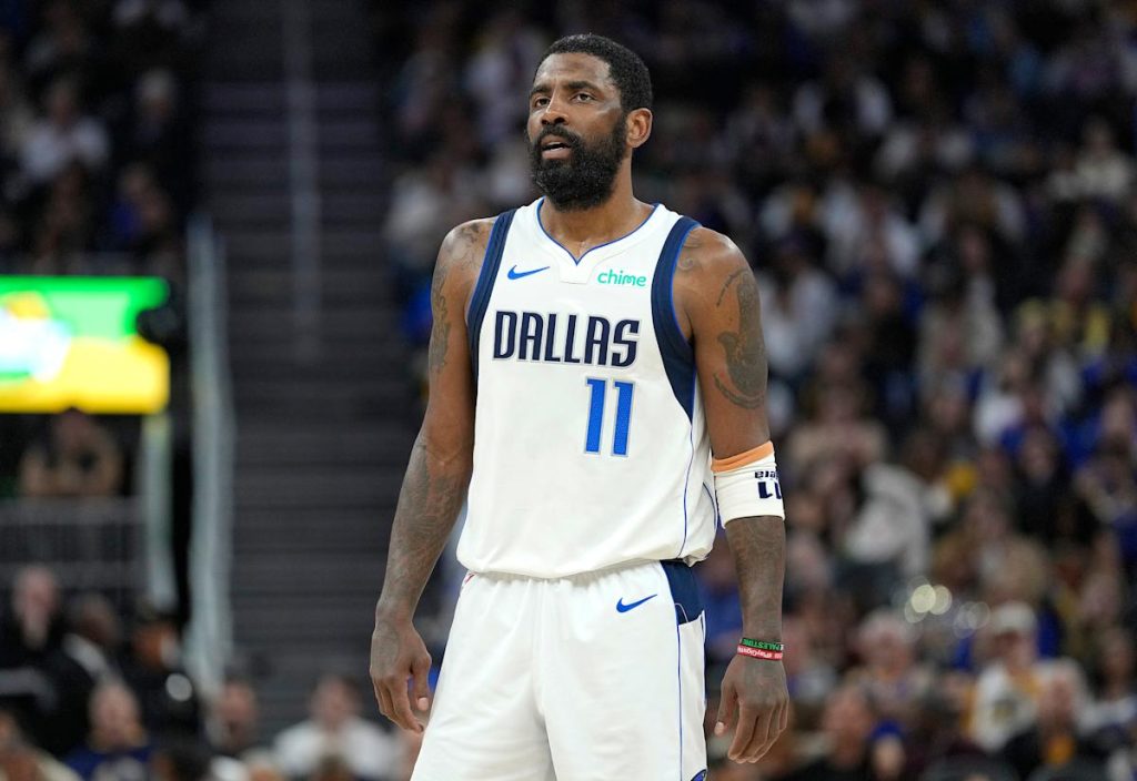 Bintang Mavericks Kyrie Irving membantu dari lantai setelah cedera lutut yang canggung di awal pertarungan dengan raja